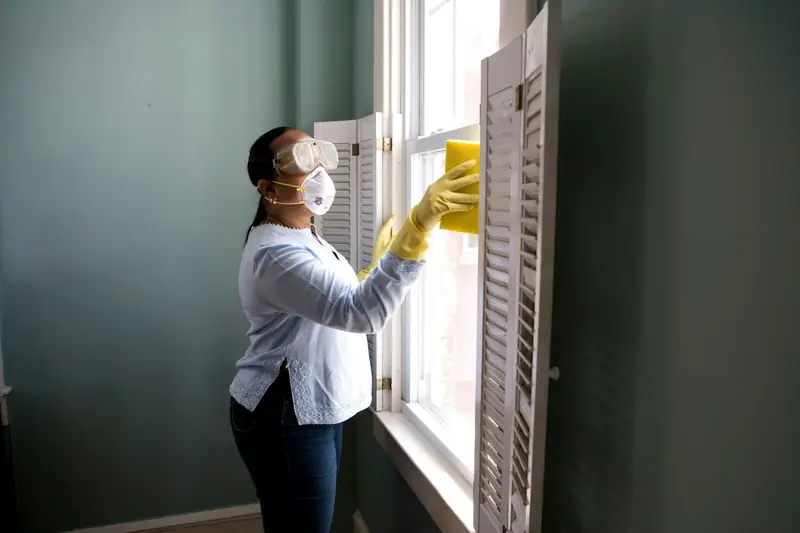 Persona de limpieza con guantes limpiando una ventana