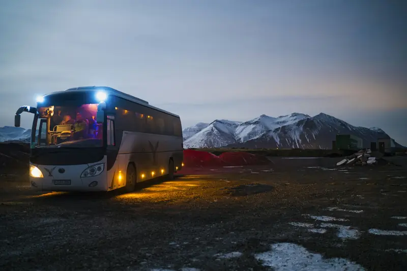 Autobús de pasajeros con luces encendidas al anochecer